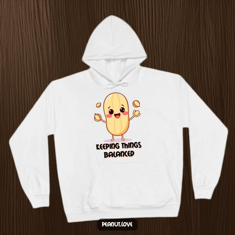 Funny hoodie depicting a cute kawaii peanut with a big smile, expertly juggling three small nuts in a playful manner.