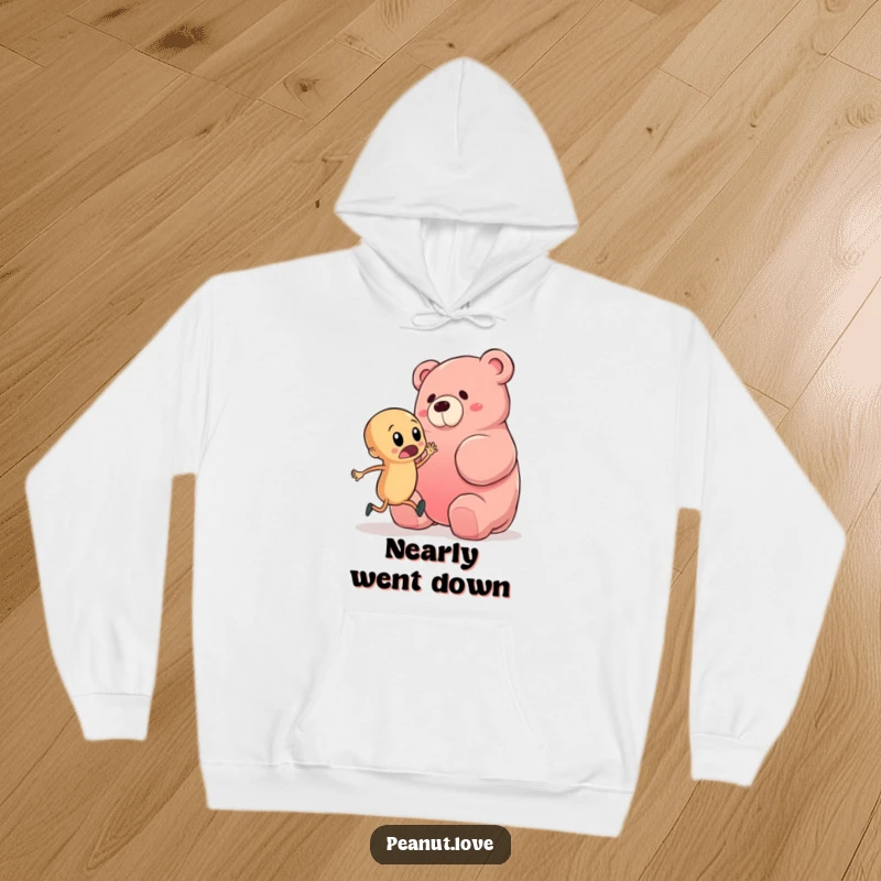 Funny hoodie depicting a startled peanut character in a comical pose, nearly tripping over an oversized gummy bear, offering warmth and humor.